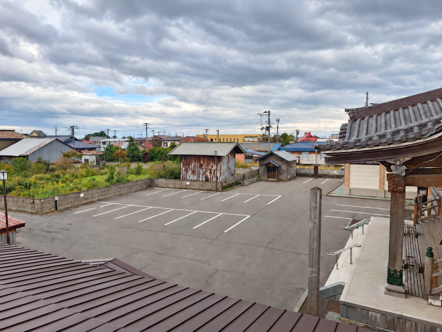 木造山正法寺の境内駐車場。白線のある駐車スペースと本堂側の建物